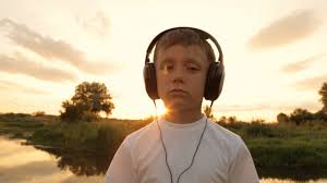 Boy listening to music through headphones in the nature under the ...